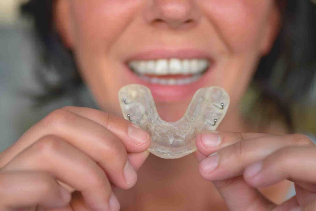 Woman suffering from bruxism holding up a guard