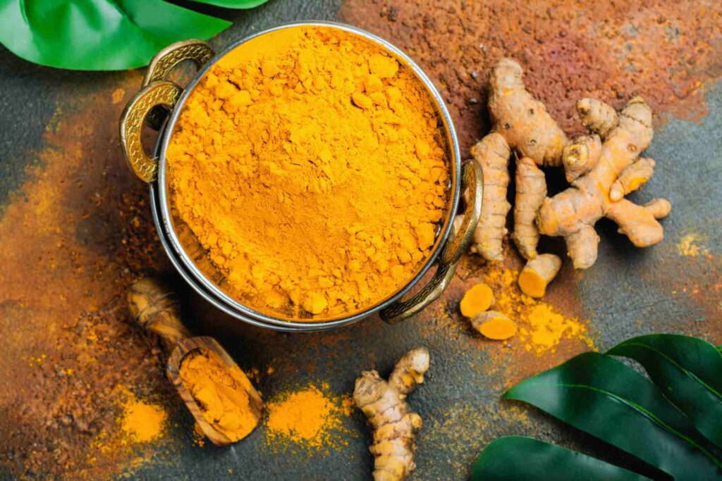 Turmeric Powder and Fresh Root on Grunge Background