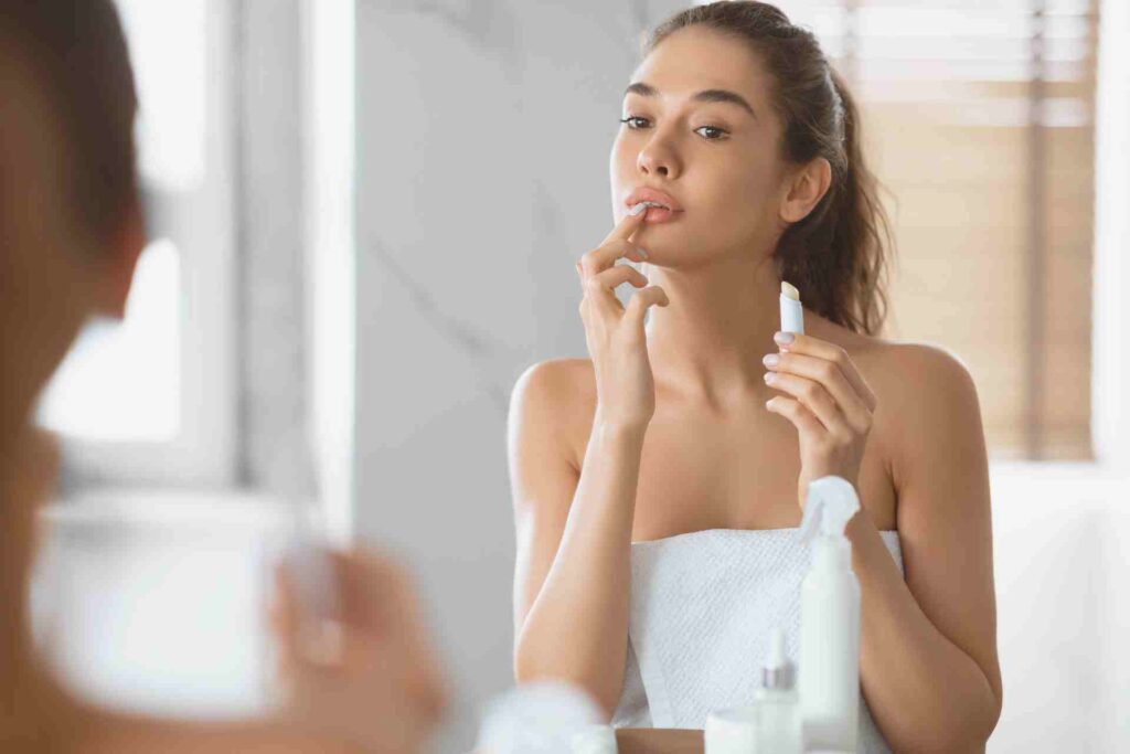 Female Applying Lip Balm Moisturizing Skin Standing in Bathroom