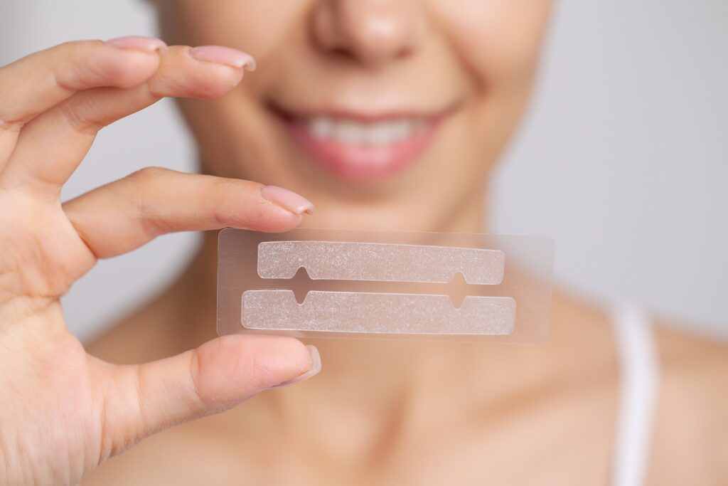 Beautiful Young Girl With White Teeth Holding in Hands Stripes For Teeth Whitening