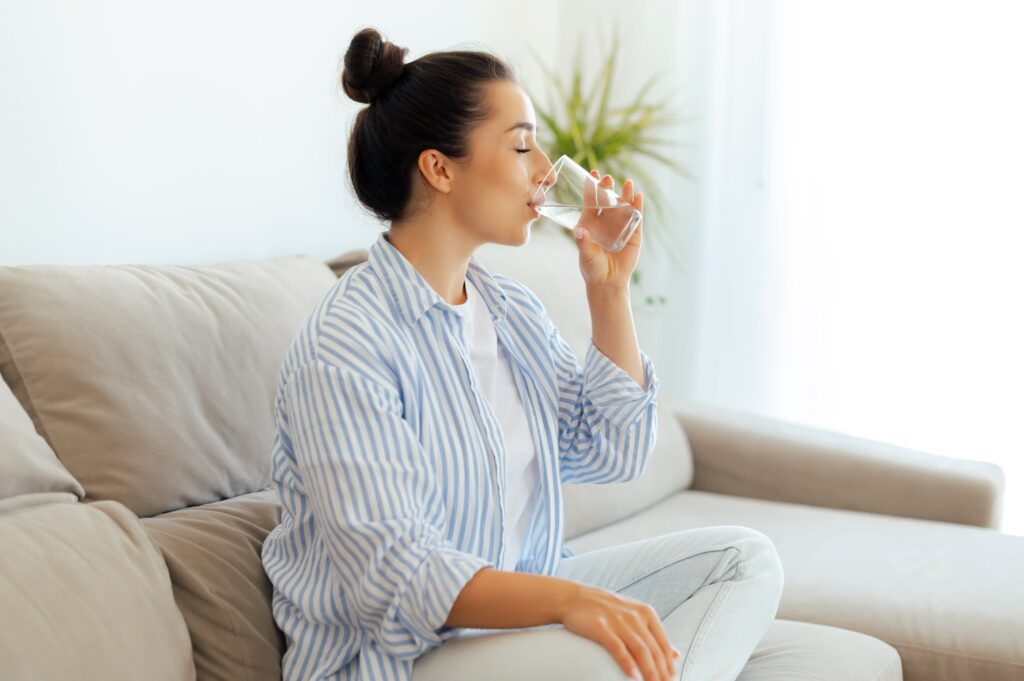Woman in casual wear is drinking a glass of water.