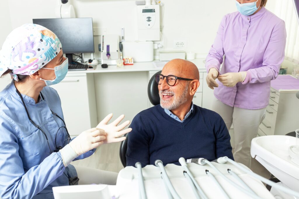 Dentist wearing surgical gloves talking to senior patient in dental clinic