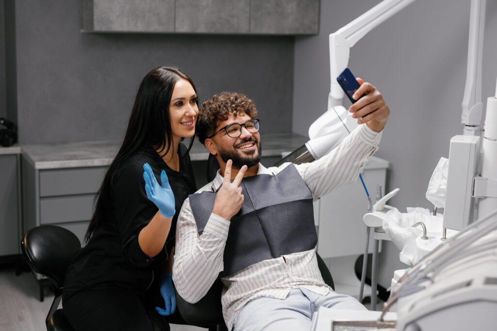 Patient and dentist taking a happy selfie in clinic