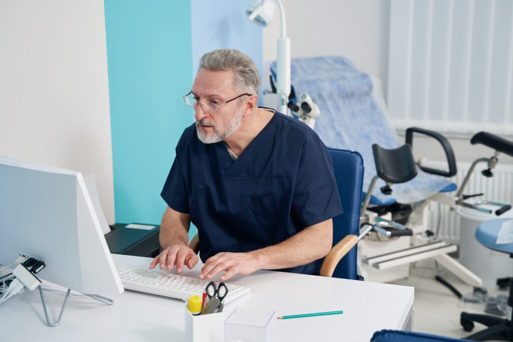 Physician working on desktop computer in his office