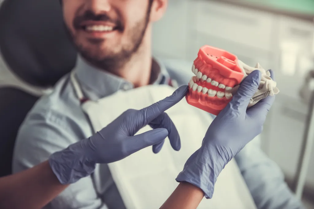 Man at Dentist Office Holding Teeth Model