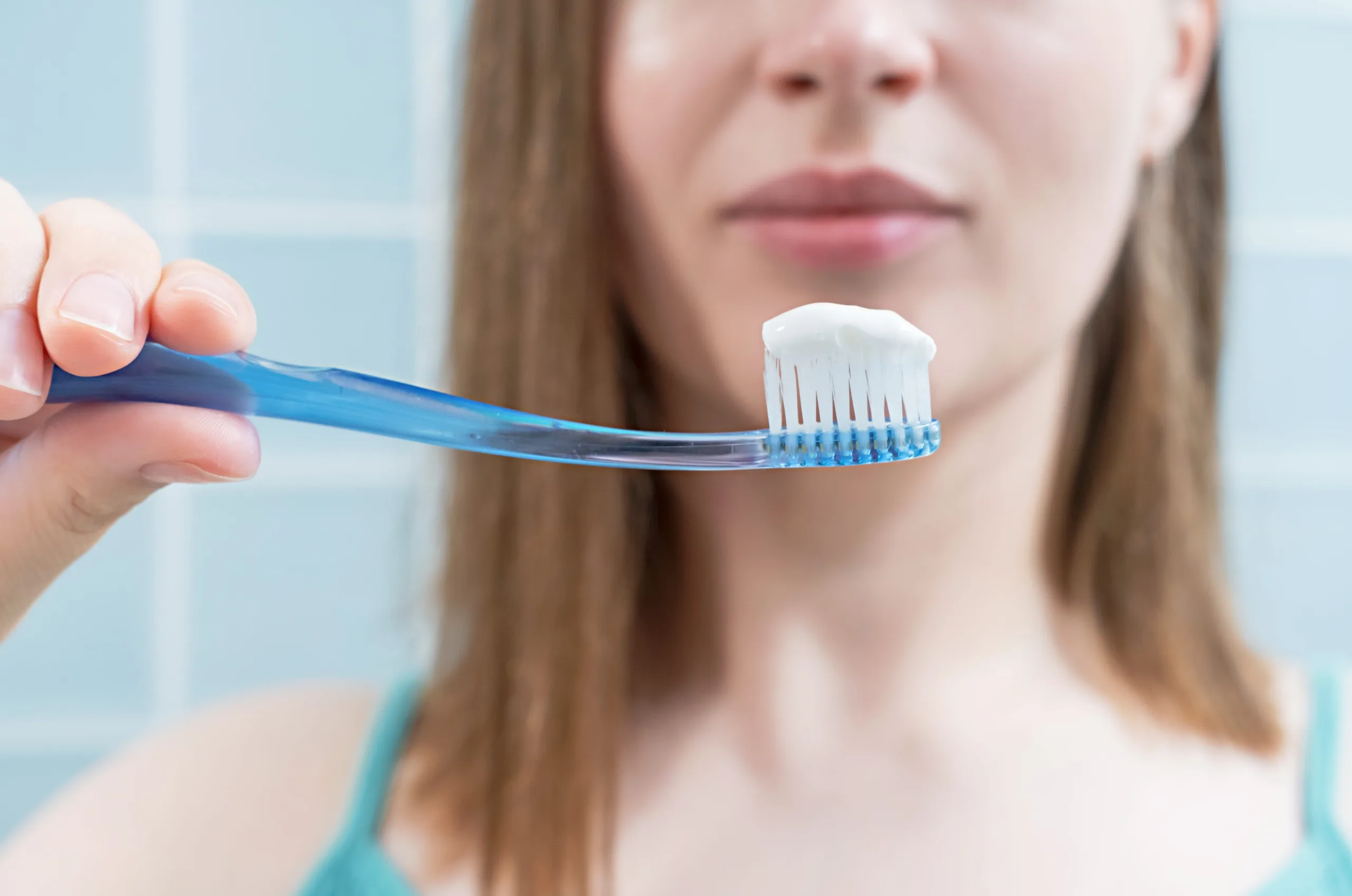 The girl brushes her teeth with toothbrush with toothpaste close-up, front view
